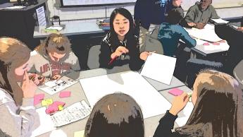 Students using paper and post it notes for a group project.
